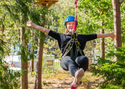 Happy woman riding a zipline in nature.