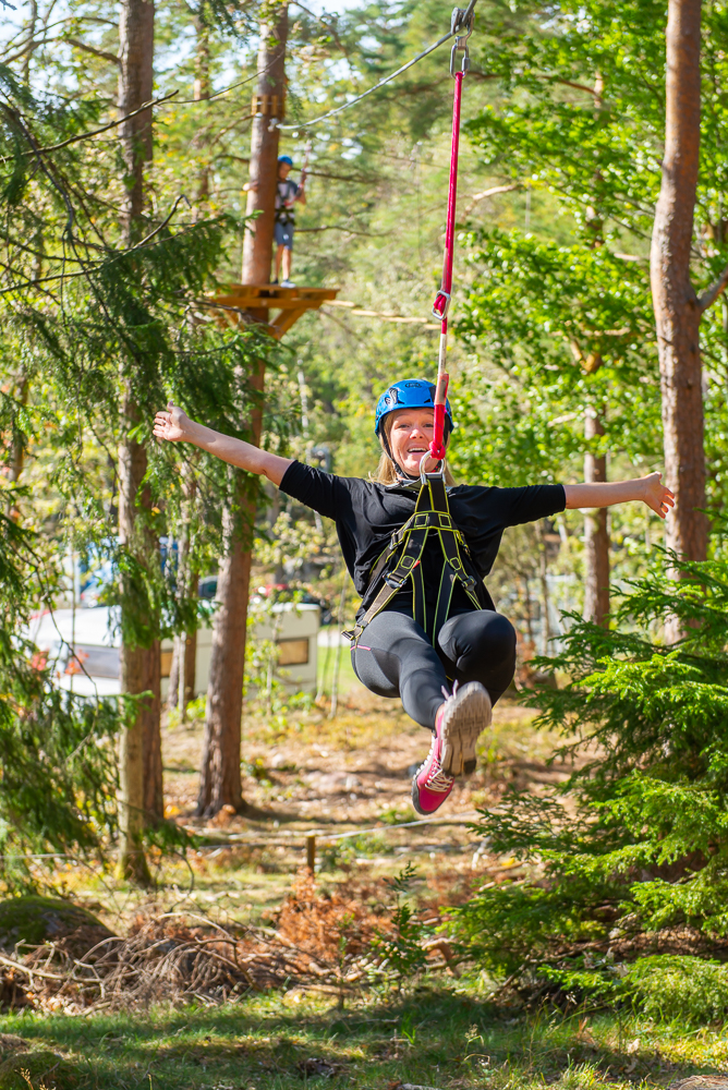 Happy woman riding a zipline in nature.